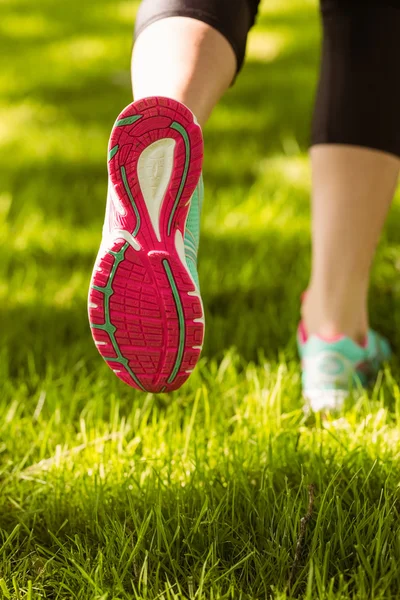 Woman in running shoes jogging on grass — Stock Photo, Image