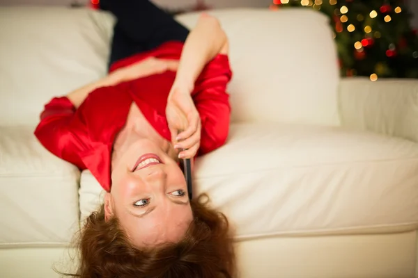 Glücklicher Rotschopf, der auf der Couch liegt und telefoniert — Stockfoto