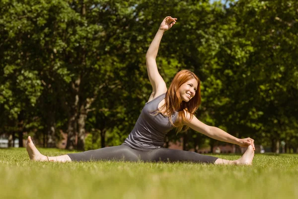 Söt rödhårig leende stretching i park — Stockfoto