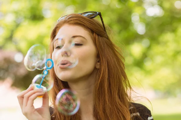 Woman blowing bubbles at park — Stock Photo, Image