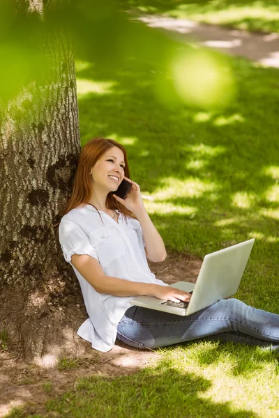 Ziemlich rothaarig am Telefon mit ihrem Laptop — Stockfoto