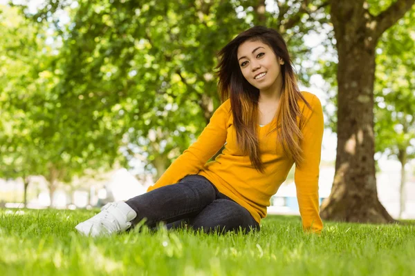 Kvinna sitter på gräs på park — Stockfoto