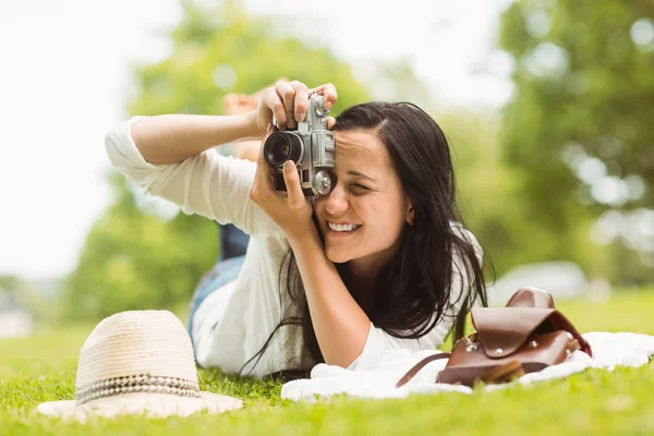 Happy brunette lying on grass taking picture — Stock Photo, Image