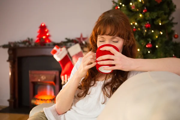 Ziemlich Rotschopf sitzt auf der Couch und trinkt heiße Schokolade — Stockfoto