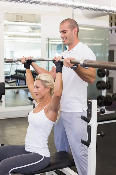 Entrenador ayudando a la mujer con la barra de elevación en el gimnasio — Foto de Stock