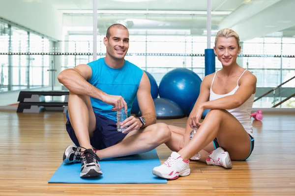 Pareja en forma sentada en el suelo en el gimnasio — Foto de Stock