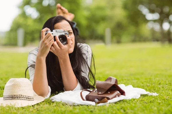 Brunette lying on grass taking picture — Stock Photo, Image