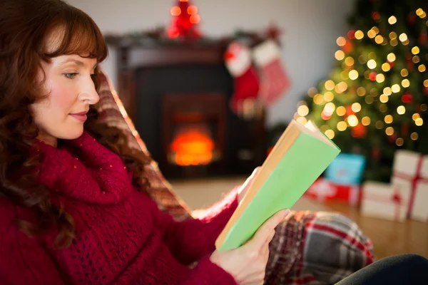 Krásná rusovláska čtení na gauči na Vánoce — Stock fotografie