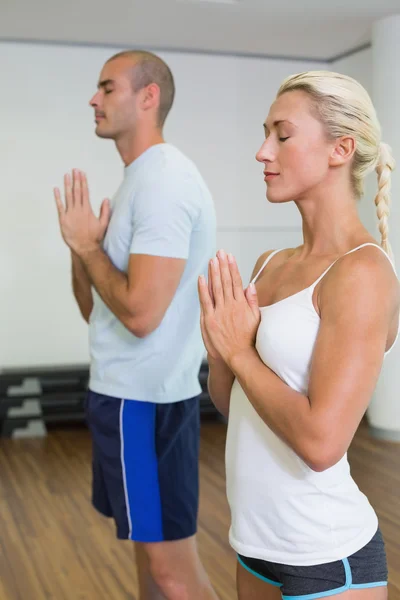Casal com mãos e olhos unidos fechados no estúdio de fitness — Fotografia de Stock