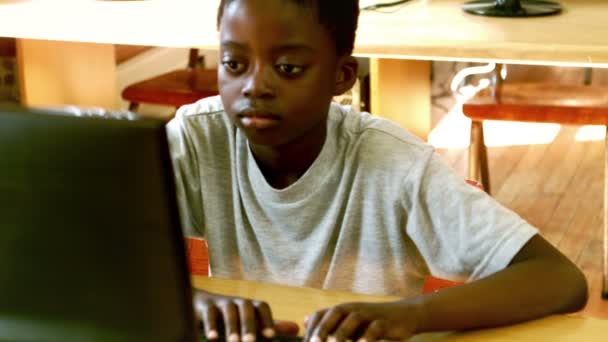 Симпатичный маленький ученик смотрит на ноутбук в классе — стоковое видео
