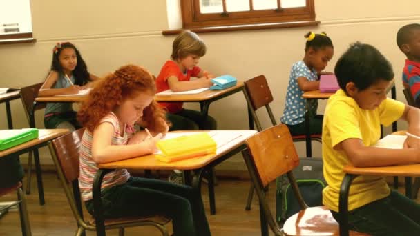 Симпатичные ученики сидят за столом в классе — стоковое видео