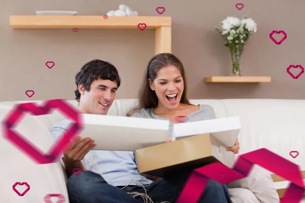 Couple on the couch opening parcel — Stock Photo, Image