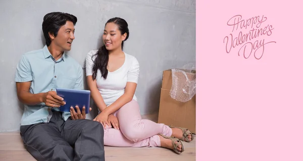 Happy couple sitting on floor using tablet — Stock Photo, Image