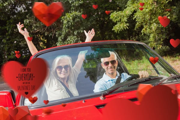 Mature couple in red cabriolet cheering — Stock Photo, Image