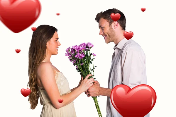 Casal segurando flores contra corações — Fotografia de Stock
