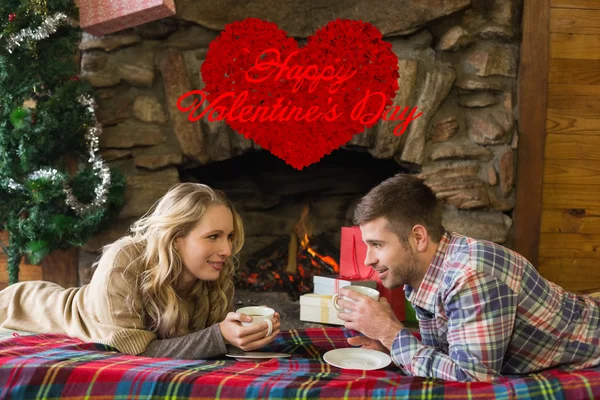 Pareja con tazas de té frente a la chimenea encendida — Foto de Stock