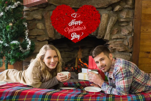 Pareja con tazas de té frente a la chimenea encendida — Foto de Stock