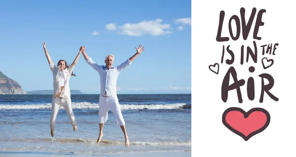 Glückliches Paar springt barfuß am Strand hoch — Stockfoto