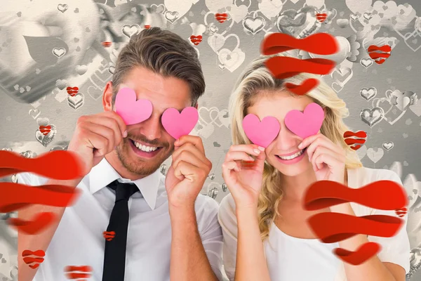 Couple holding pink hearts over eyes — Stock Photo, Image