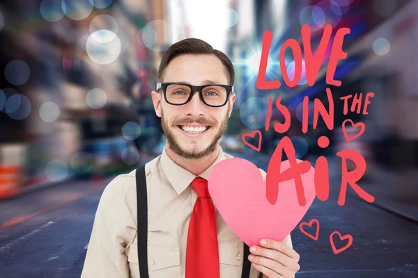 Composite image of geeky hipster smiling and holding heart card — Stock Photo, Image