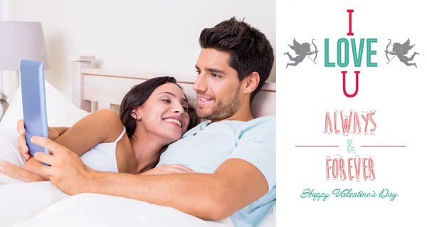 Attractive couple lying in bed with tablet pc — Stock Photo, Image