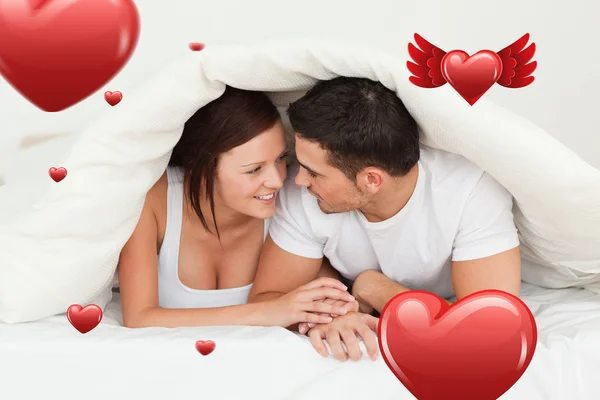 Happy couple hiding under a blanket — Stock Photo, Image