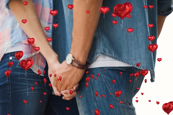 Composite image of hip young couple holding hands — Stock Photo, Image