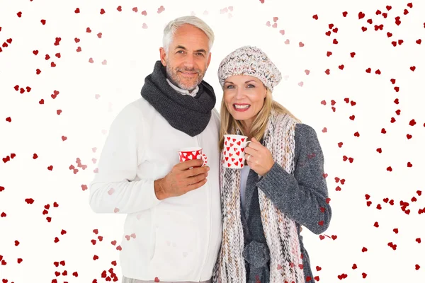 Couple in winter fashion holding mugs — Stock Photo, Image