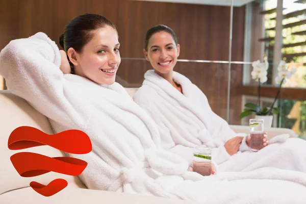 Smiling women in bathrobes sitting on couch — Stock Photo, Image