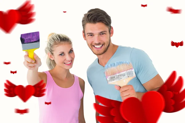 Couple smiling and holding paintbrushes — Stock Photo, Image