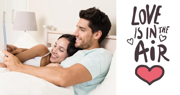 Attractive couple lying in bed with tablet pc — Stock Photo, Image