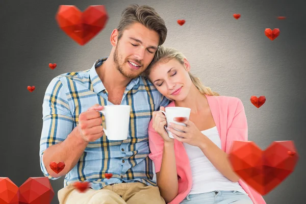 Casal atraente sentado segurando canecas — Fotografia de Stock