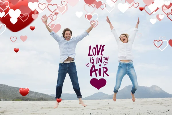 Fröhliches junges Paar springt am Strand — Stockfoto