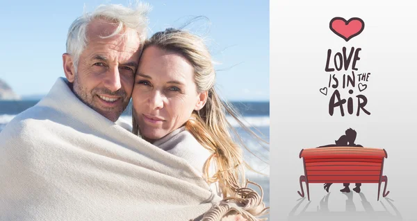 Smiling couple wrapped up in blanket — Stock Photo, Image