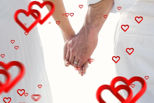 Samengestelde afbeelding van bruid en bruidegom hand in hand close-up — Stockfoto