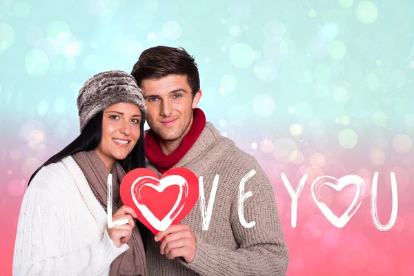 Pareja sonriendo sosteniendo el corazón rojo — Foto de Stock