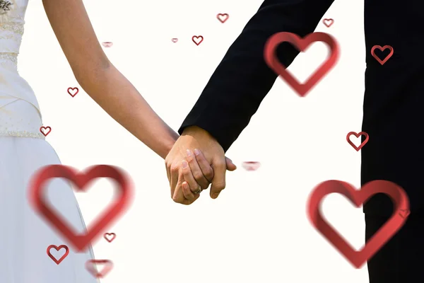 Composite image of mid section of newlywed couple holding hands — Stock Photo, Image