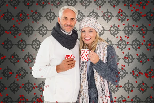 Happy couple in winter fashion holding mugs — Stock Photo, Image