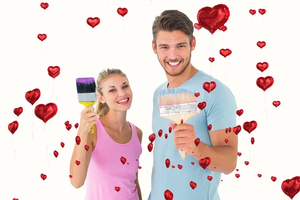 Couple smiling and holding paintbrushes — Stock Photo, Image