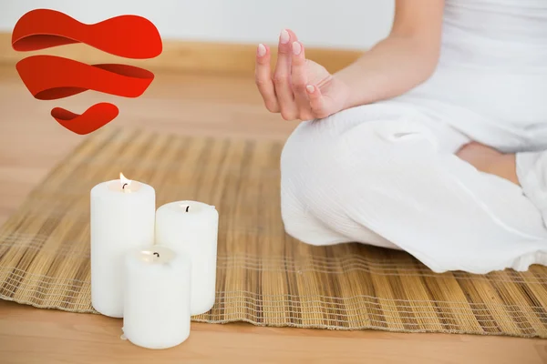 Woman sitting in lotus pose beside white candles — Stock Photo, Image