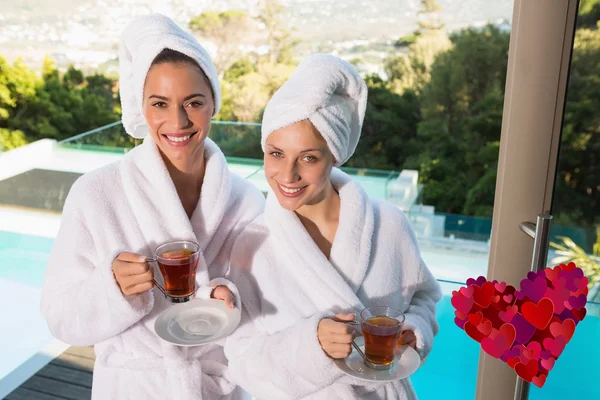 Mulheres sorridentes em roupões de banho tomando chá — Fotografia de Stock