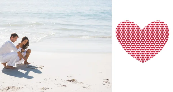 Bonito casal desenhando um coração na areia — Fotografia de Stock