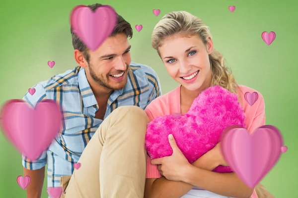 Couple sitting holding heart cushion — Stock Photo, Image