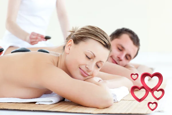 Composite image of young couple having a massage with hot stone — Stock Photo, Image