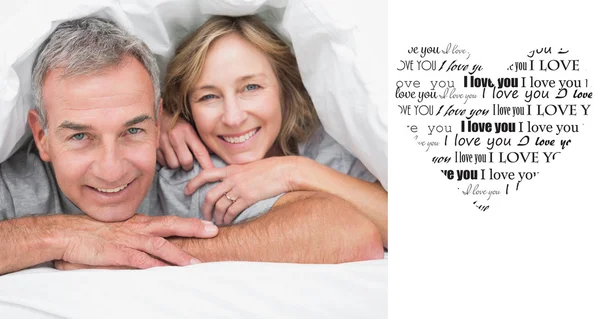 Zusammengesetztes Bild eines verliebten Paares unter der Bettdecke — Stockfoto
