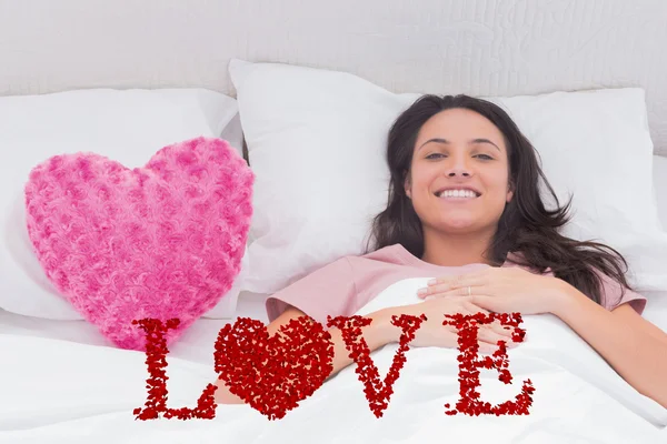 Mujer acostada en su cama junto a un corazón rosado —  Fotos de Stock