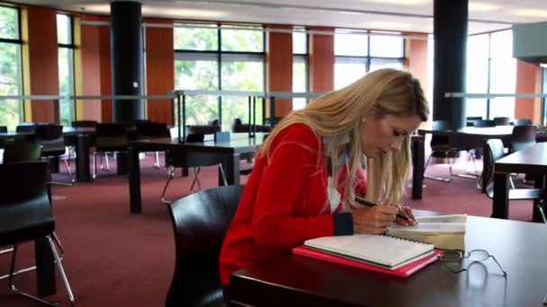 Student with reading glasses studying at library desk — Stock Video