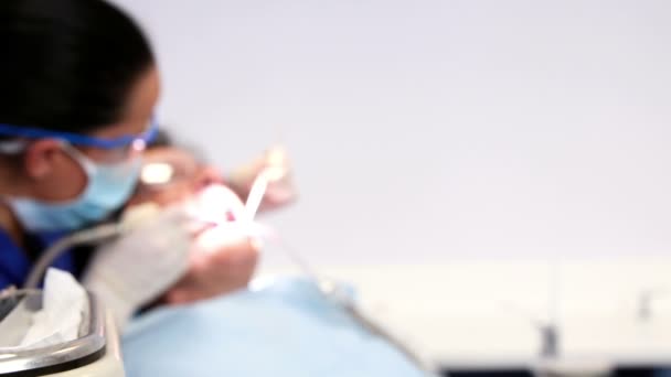 Dentista che esamina i denti di un paziente sulla sedia del dentista — Video Stock