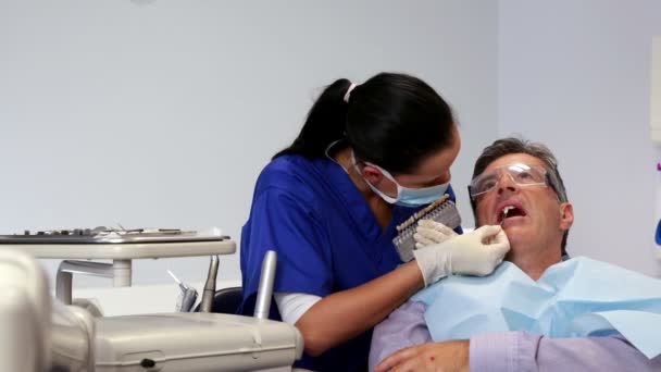 Стоматолог сравнивает оттенки белого с зубами пациентов — стоковое видео