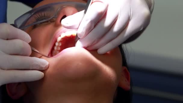 Стоматолог осматривает зубы пациента в кресле стоматолога — стоковое видео